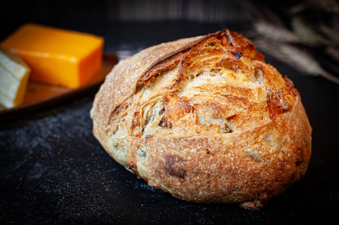 Artisan Jalapeño Cheddar Sourdough loaf with a golden crust and visible jalapeño and cheddar pieces.